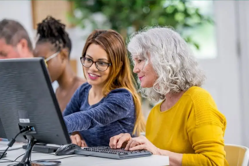 Two older adults learning together on a laptop